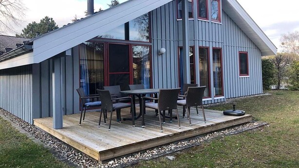 A modern house with a deck, large windows, and a chimney.