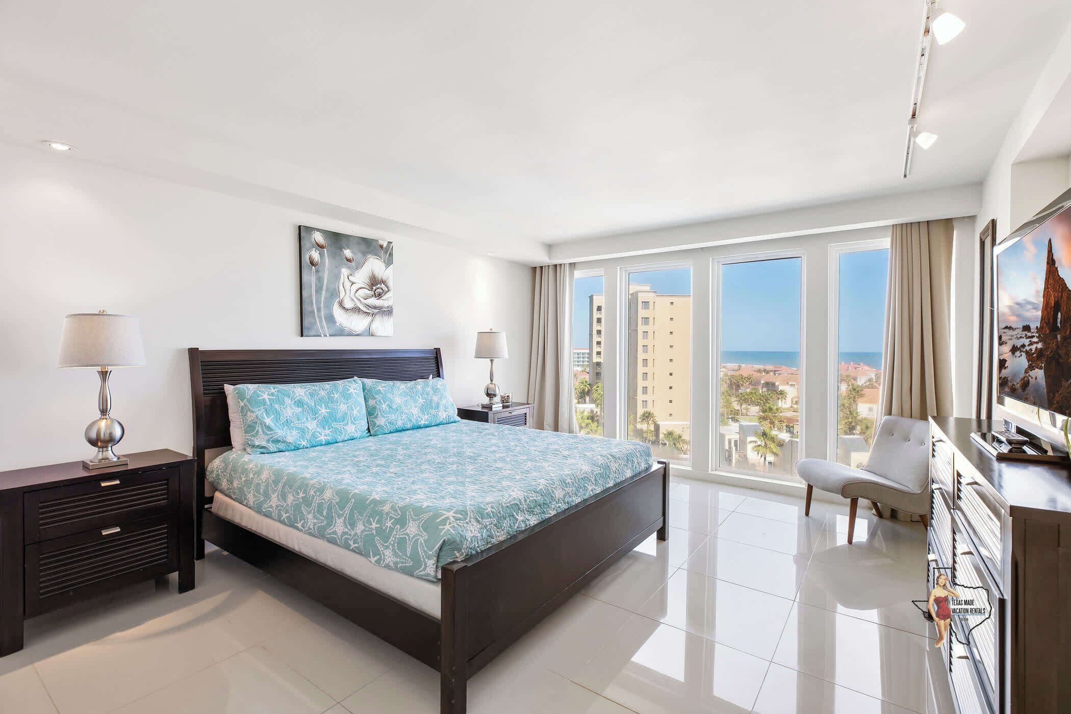 A modern hotel room with a large bed, a desk, and a view of the cityscape.
