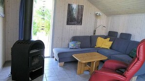 Tunnelmallinen olohuone, jossa on sohva, punainen nojatuoli, pieni puinen pöytä ja musta puukamiina.
