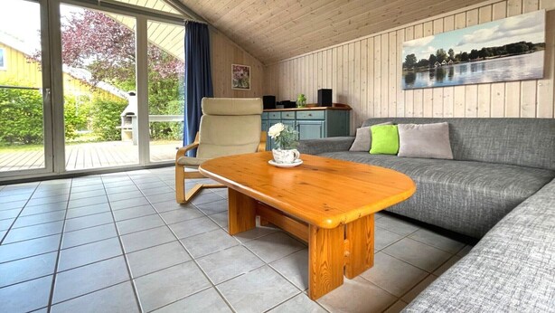 Ein gemütliches Wohnzimmer mit Couchtisch aus Holz, grauem Sofa und einem Gemälde eines Sees.