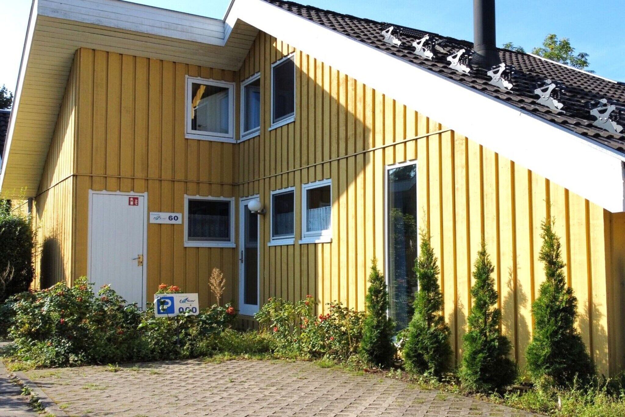 A yellow building with a white door, multiple windows, and a chimney.