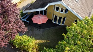 Eine Luftaufnahme eines zweigeschossigen Hauses mit einer überdachten Terrasse und einem pinken Sonnenschirm.