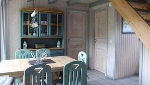 A dining area with a wooden table, teal chairs, and a cabinet with glass doors. - skandinavisches Ferienhaus in Mirow (Granzow)