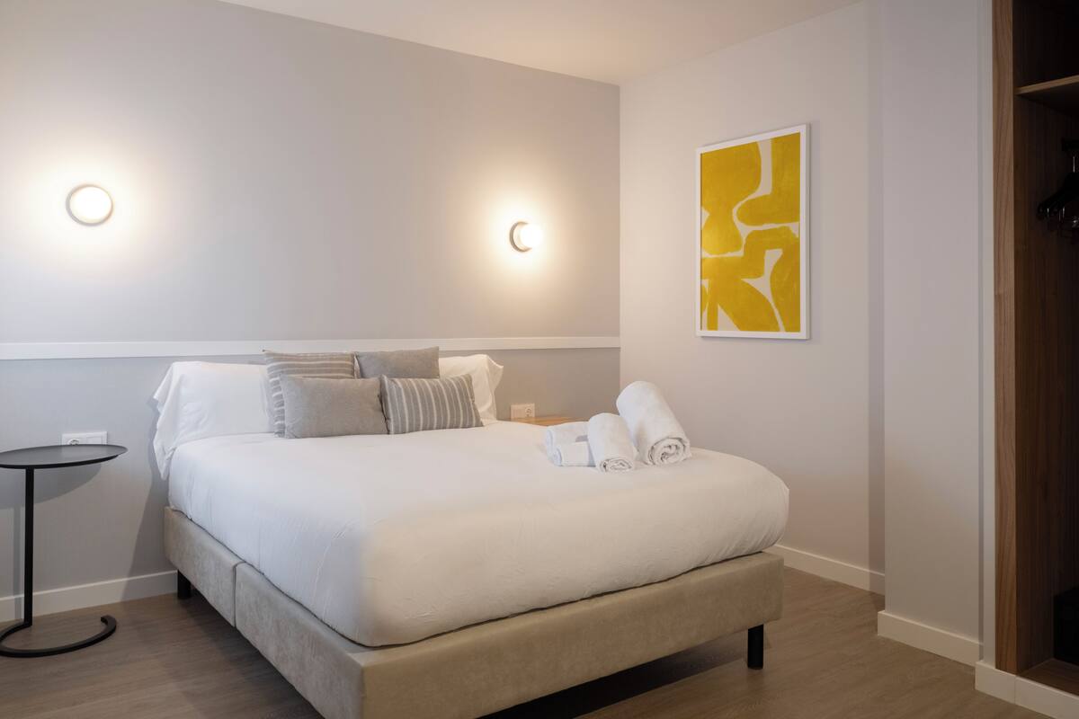 A hotel room with a bed, bedside tables, a wall-mounted artwork, and a wooden door.