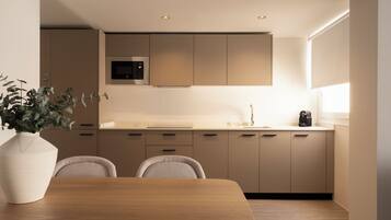 A modern kitchen with a wooden dining table, recessed ceiling lights, and a built-in microwave.