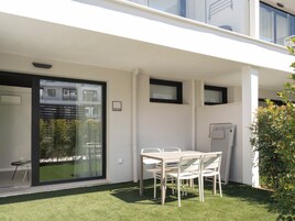 A modern apartment with a balcony, a dining area with a table and chairs, and a small garden.