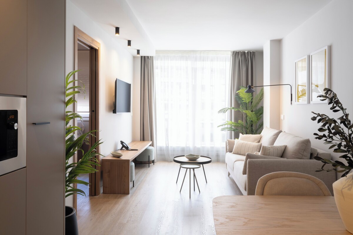 A modern living room with a sofa, coffee table, and a TV mounted on the wall.