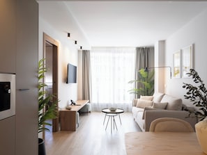 A modern living room with a sofa, coffee table, and a TV mounted on the wall. - Meral Units (Fuengirola)