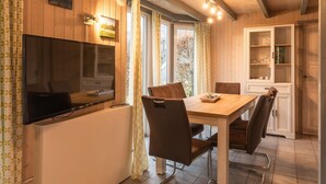 Un comedor acogedor con una mesa de madera, sillas, un televisor y un mueble.