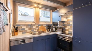 Una cocina compacta con lavavajillas Bosch, microondas, cafetera y estufa.