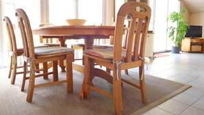 Un coin repas avec une table et des chaises en bois, un téléviseur et une plante en pot.