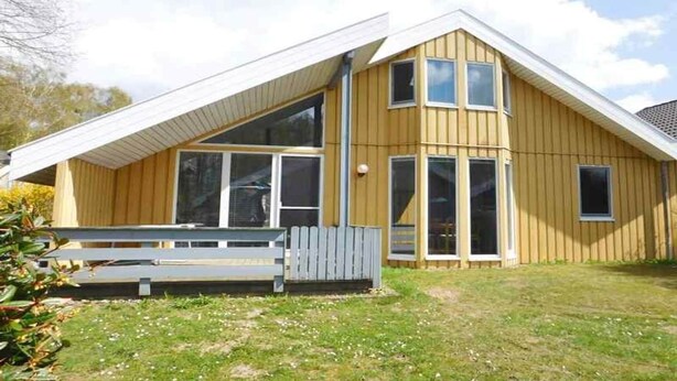 Une maison en bois avec un toit en pente, de grandes fenêtres et un petit porche.