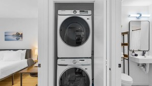 A hotel room with a bed, a desk, a washing machine, a toilet, and a sink. - The Cloudbreak Townhome - 88 Walkscore! (Seattle)