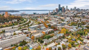 An aerial view of a city with a mix of residential and commercial buildings, a large stadium, and a body of water in the background. - The Cloudbreak Townhome - 88 Walkscore! (Seattle)