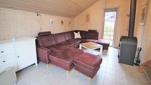 A cozy living room with a sectional sofa, a coffee table, and a fireplace. - Ferienhaus im skandinavischen Stil (Granzow)