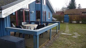 A blue house with a deck, a table, and chairs. - Ferienhaus im skandinavischen Stil (Granzow)