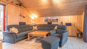 A cozy living room with a sectional sofa, a coffee table, and a wooden cabinet with a radio. - skandinavisches Ferienhaus in Mirow (Granzow)