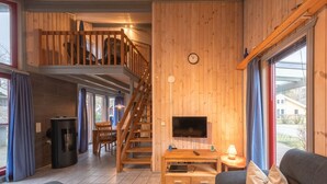 A wooden interior with a TV, sofa, and staircase. - skandinavisches Ferienhaus in Mirow (Granzow)