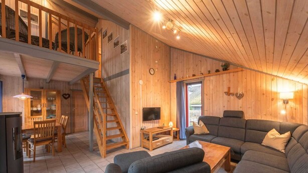 A wooden interior with a staircase, a dining area, and a living room with a sofa and TV. - skandinavisches Ferienhaus in Mirow (Granzow)