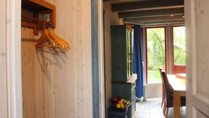 Een gang met houten wanden, een blauwe kast en een eethoek met een tafel en stoelen.
