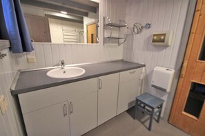 A bathroom with a sink, cabinets, a mirror, a towel rack, and a toilet. - exklusives skandinavisches Ferienhaus (Granzow)
