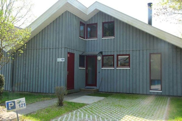 A two-story building with a red door and windows, a chimney, and a parking sign. - exklusives skandinavisches Ferienhaus (Granzow)