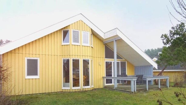 Un bâtiment jaune doté d’une grande porte vitrée et d’un espace extérieur abrité avec des sièges.