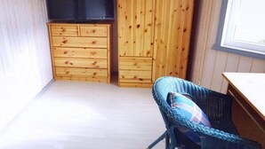Une petite pièce en bois, avec une seule chaise, une armoire en bois et un téléviseur.