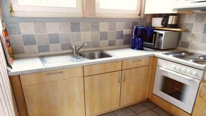 Une cuisine de taille réduite, équipée d’un évier, d’une cuisinière et d’un four à micro-ondes.