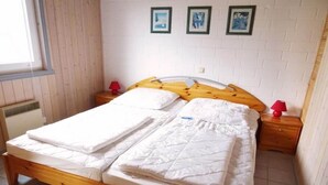 Un lit double avec un cadre en bois, une literie blanche et deux tables de chevet avec des lampes rouges.