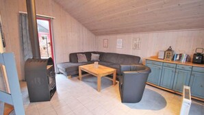 A cozy room with a sofa, a small table, a trash bin, and a kitchenette area. - skandinavisches Ferienhaus in Mirow (Granzow)