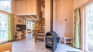 Et træpanelt interiør med pejs, tv og trappe op til et højere niveau.