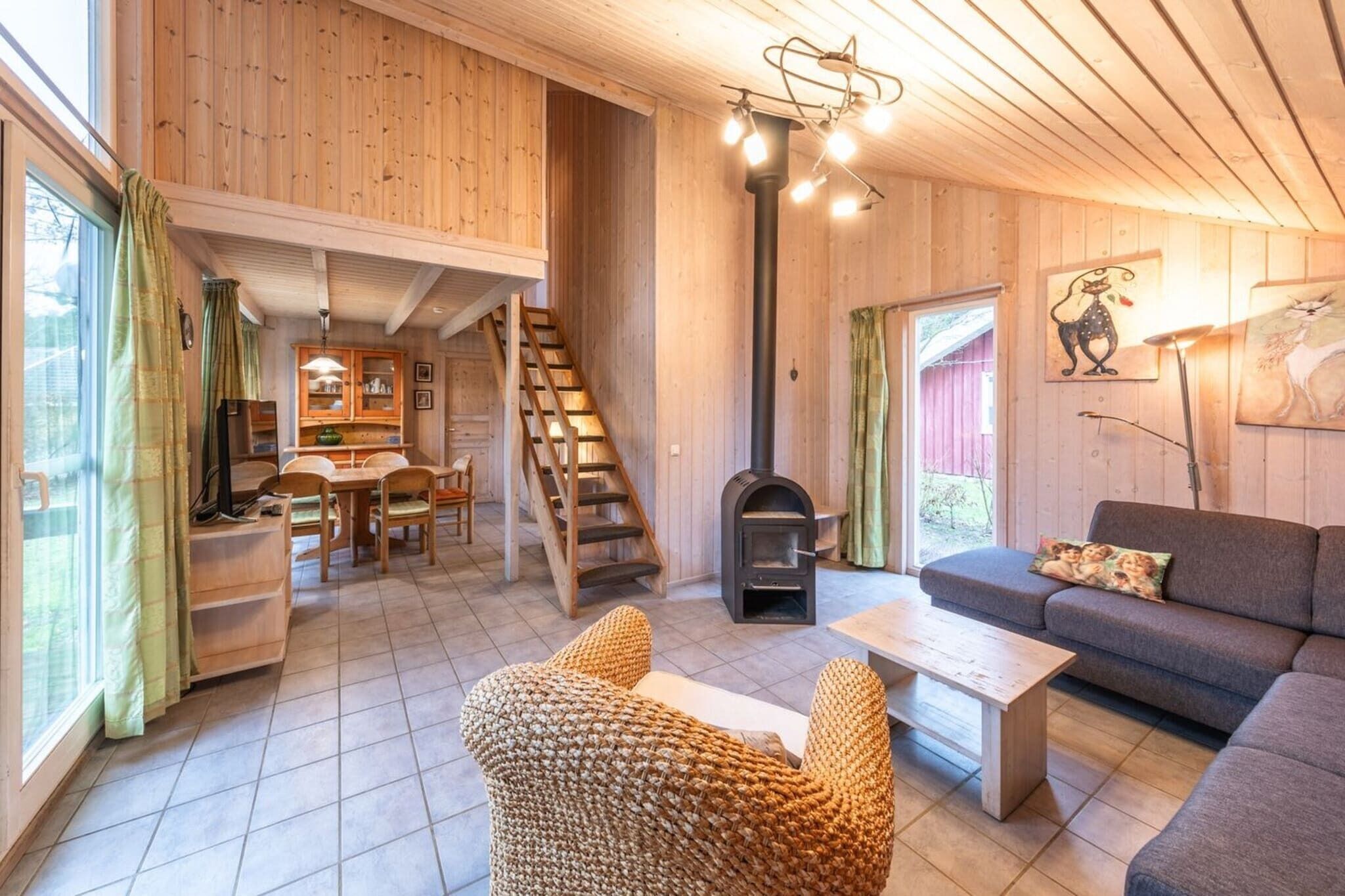 A cozy cabin interior with a wooden interior, a fireplace, a sofa, and a dining area.