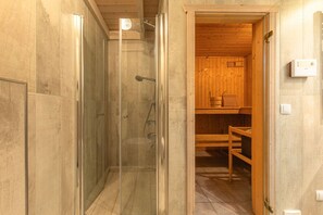 A wooden cabin interior with a glass-enclosed shower area and a visible wooden sauna. - Ferienhaus im Ferienpark Mirow (Granzow)