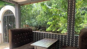 Un rincón acogedor con dos sillones mullidos y una mesita baja, rodeado por una pared de diseño en blanco y negro con patrón de chevrón y vistas a follaje exuberante.