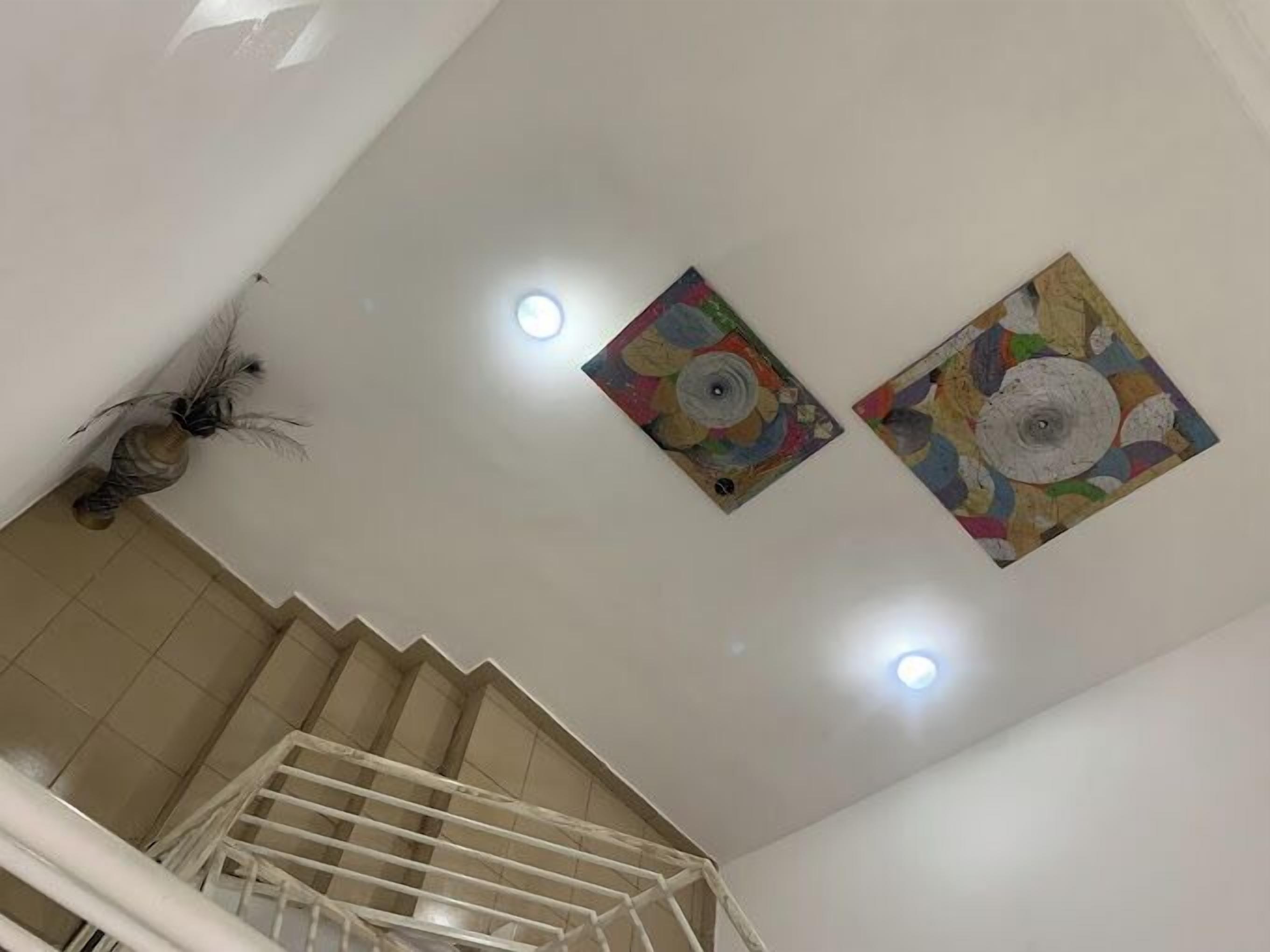 Una escalera con barandilla blanca, techo con dos obras de arte murales coloridas e iluminación empotrada.