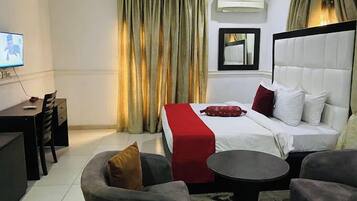 Una habitación de hotel con una cama, un escritorio, una silla, un sofá y una mesita.