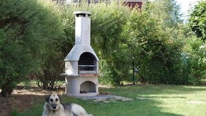 Un horno de piedra al aire libre en un jardín, con un perro descansando cerca.