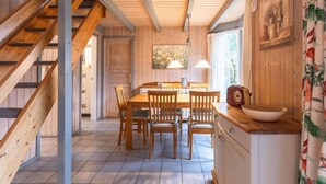 A wooden interior with a staircase, a dining area with a table and chairs, and a kitchen counter.