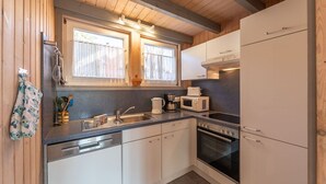 Une cuisine compacte avec des meubles blancs, un four encastré, un four à micro-ondes et un évier.