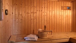 A wooden sauna room with a bench, a wooden bucket, and a towel. - skandinavisches Ferienhaus in Mirow (Granzow)