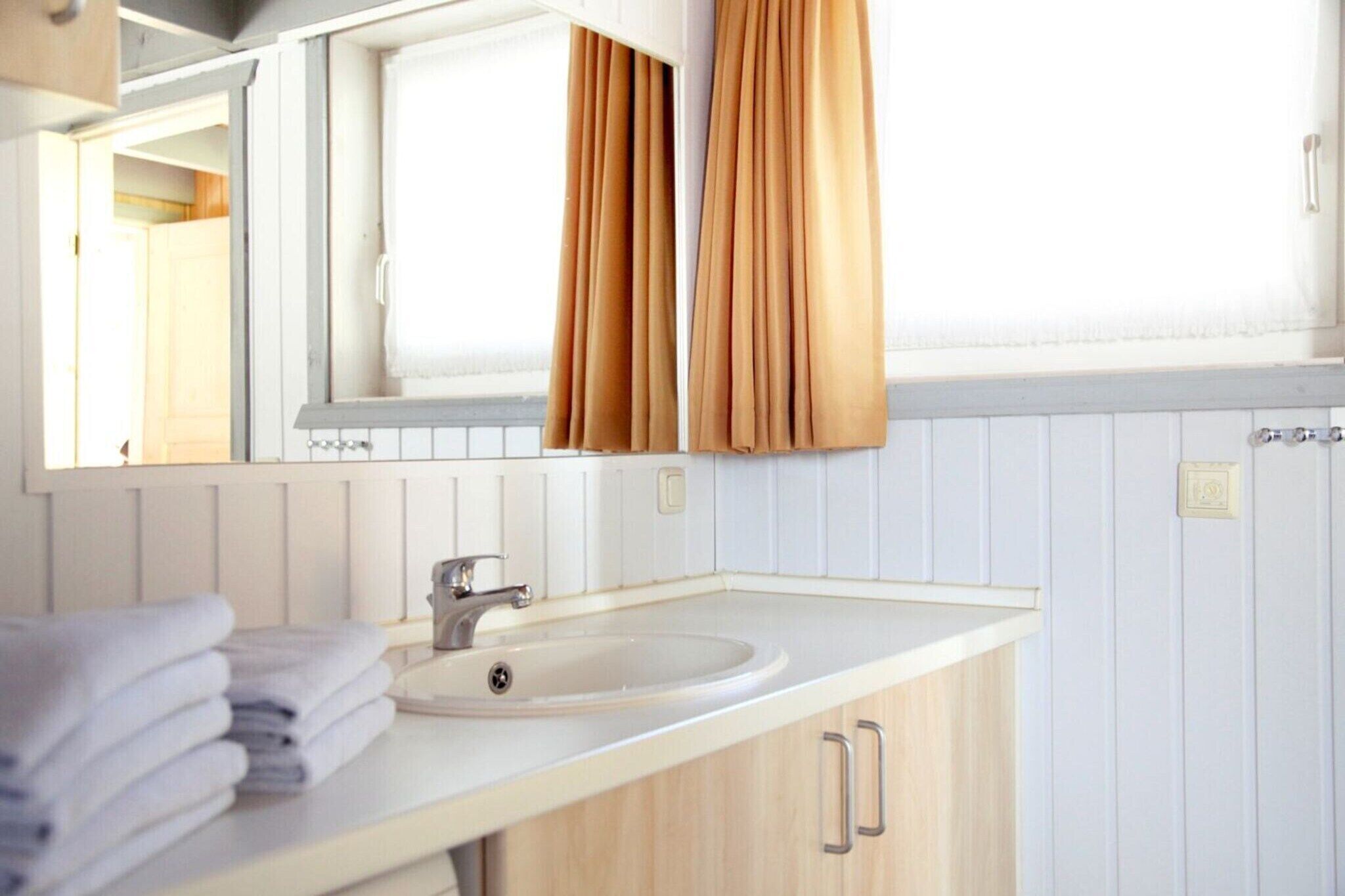 A bathroom with a white sink, a mirror, and a window with curtains.
