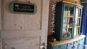 Eine Holztür mit einer Willkommensschild und einem Schrank mit Glastüren.