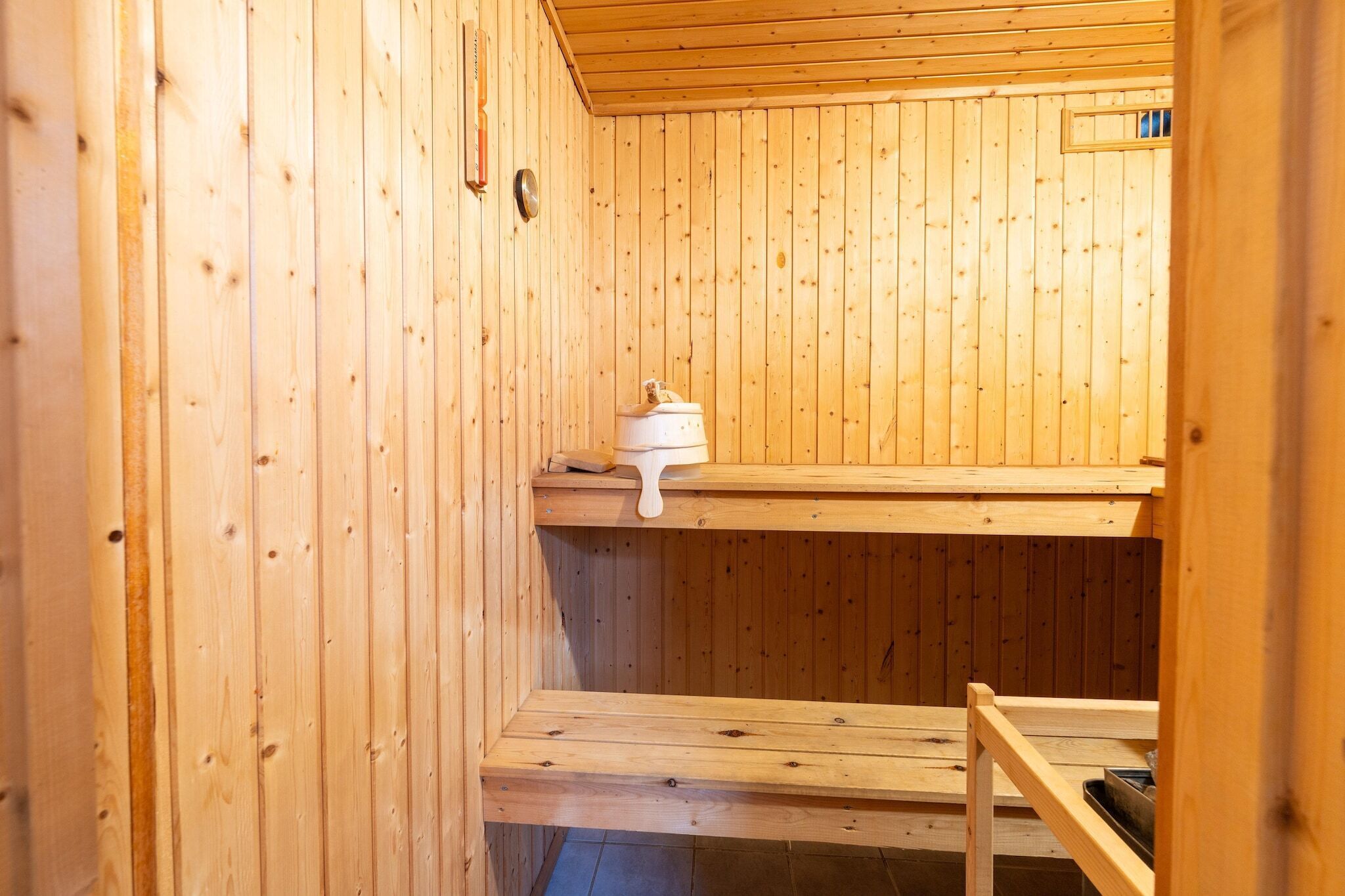 Ein Holzsaunaraum mit einer Sitzbank, Ablagefläche und einem kleinen Heizgerät.
