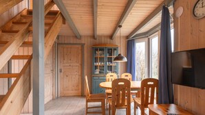 A wooden interior with a dining area, a TV, and a clock on the wall. - Ferienhaus im skandinavischen Stil (Granzow)