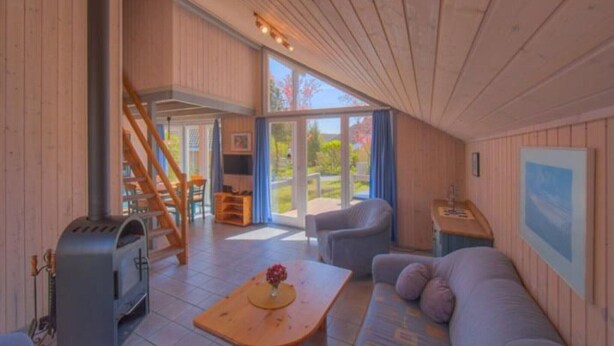 Un interno accogliente con rivestimenti in legno, un camino, un divano e una zona pranzo.