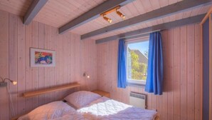 Un'accogliente camera da letto in legno con un letto, una finestra con tende e un lampadario a parete.