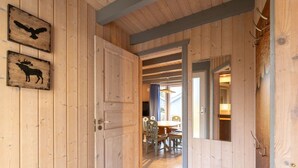 Un intérieur en bois comprenant un coin repas, une porte donnant sur une autre pièce et des silhouettes d’animaux fixées au mur.