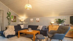 A cozy living room with a dark grey sofa, a wooden coffee table, and a grey armchair. - skandinavisches Ferienhaus in Mirow (Granzow)