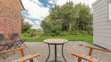 A patio with a round table and chairs, surrounded by a brick wall and a wooden fence.